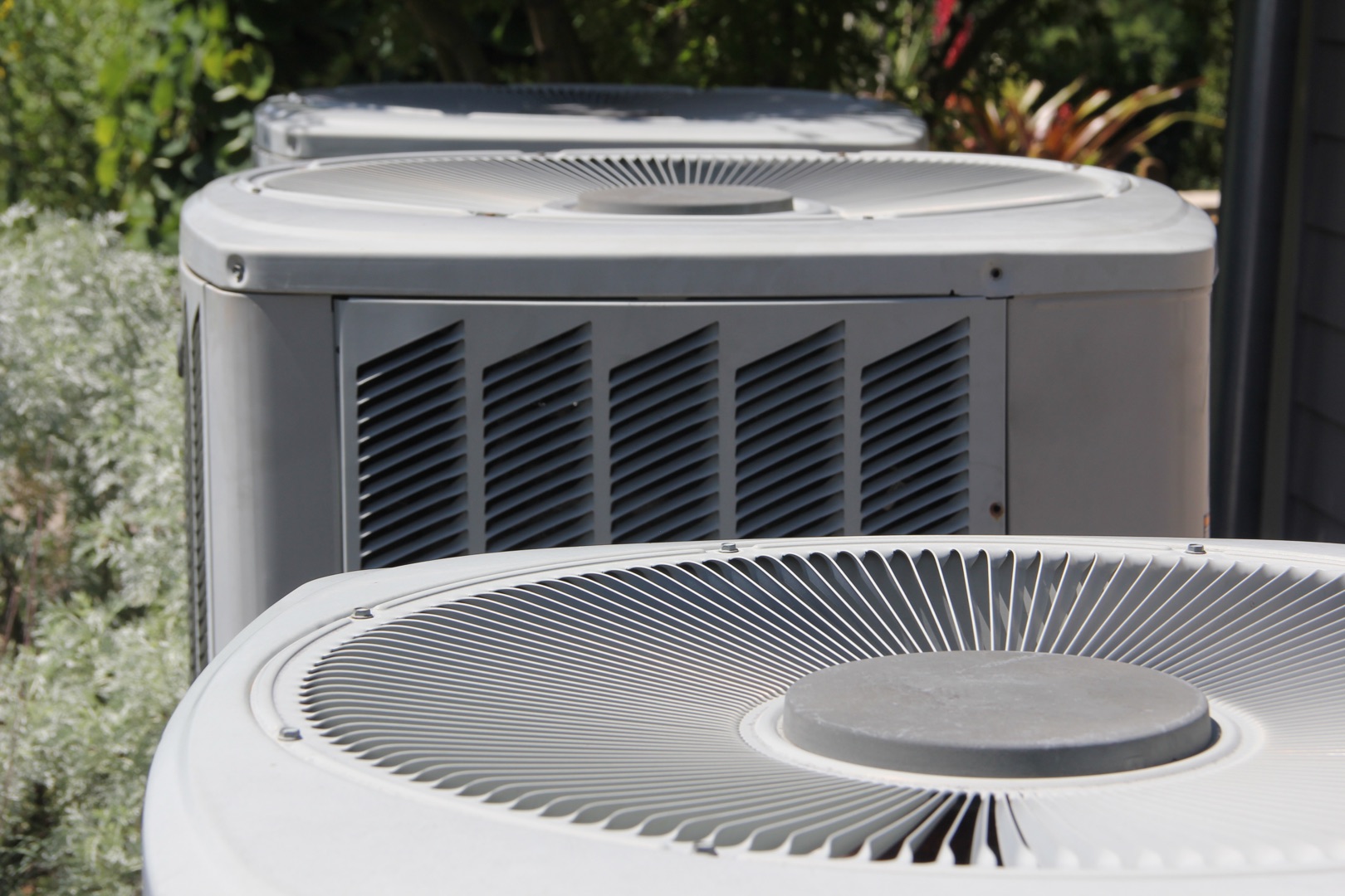 about-02 Close-up view of multiple outdoor air conditioning units lined up, perfect for a landing page header, showcasing their top fan covers and metal vent panels.