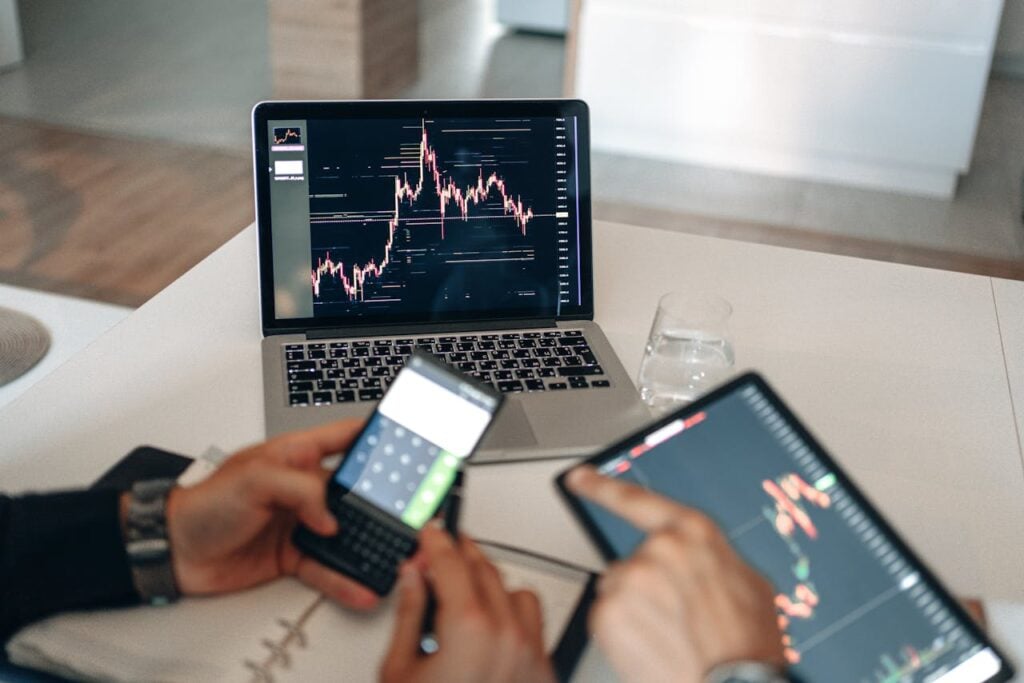 The Entrepreneur’s Guide to Turning Ideas Into Profitable Hands using digital devices for financial analysis at a modern desk setup.