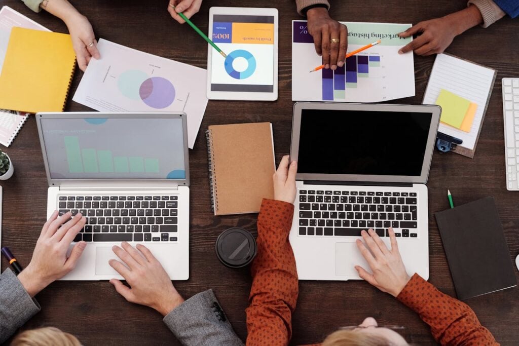 Overcoming Challenges Lessons Every Entrepreneur Must Learn Overhead view of a team discussing digital marketing strategies with laptops and charts.