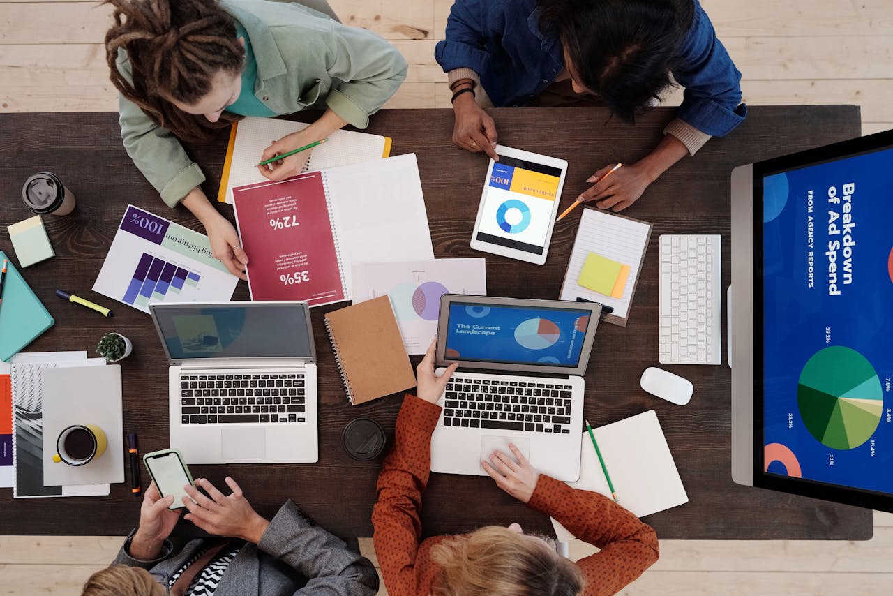 who-we-are-img A diverse team collaborating on digital marketing strategies at a desk, using laptops and tablets.