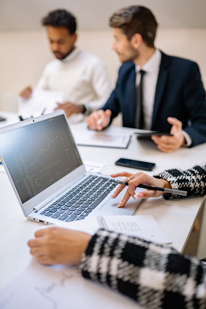 experience-img Professionals collaborating with technology to analyze stock market trends on a laptop.