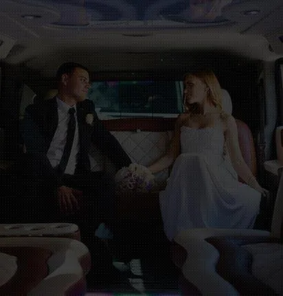tmpwg4dykdr A bride and groom pose together beside a white bus, smiling and dressed in wedding attire.