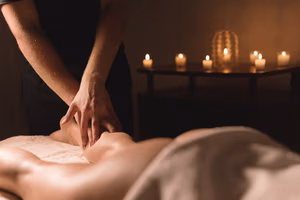 Close-up of male hands doing calf massage of female legs in a dark room with candles in the background. Cosmetology and spa treatments Close-up of male hands doing calf massage of female legs in a dark room with candles in the background. Cosmetology and spa treatments.