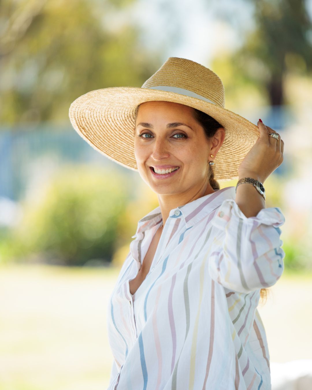 Kristina Jones - CEO of Cat in a Hammock Woman smiling and holding a straw hat with outdoor landscape in the background
