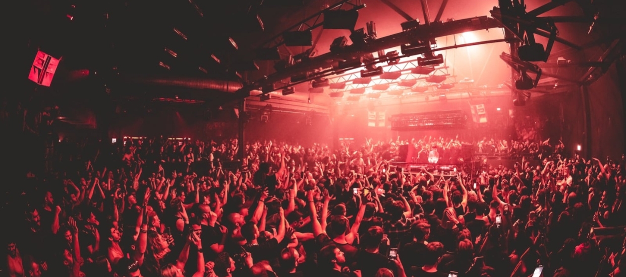 Large crowd at a Unreal Germany with industrial lighting, representing the global scale of the hard techno movement and current industry crisis.