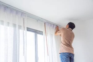 Top Tips to Keep Your Home Cool with an Efficient Cooling System 2 man fixing curtains