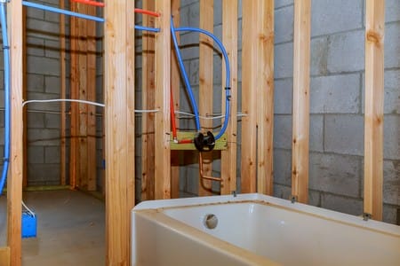 How Much Does Plumbing Cost for a New House? 3 Bathroom remodel showing under floor plumbing work connecting installation of pipes for water for new buildings