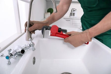 How Much Does Plumbing Cost for a New House? 4 Professional plumber fixing water tap in kitchen closeup
