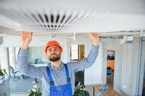 Technician-service-checking-and-repairing-air-conditioner-indoors Service technician checking and repairing air condition