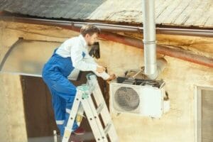 Understanding Heating System Ratings and Certifications 3 HVAC technician repairing AC unit – air conditioning & heating services.
