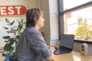 A man at a desk using a laptop looking out the window