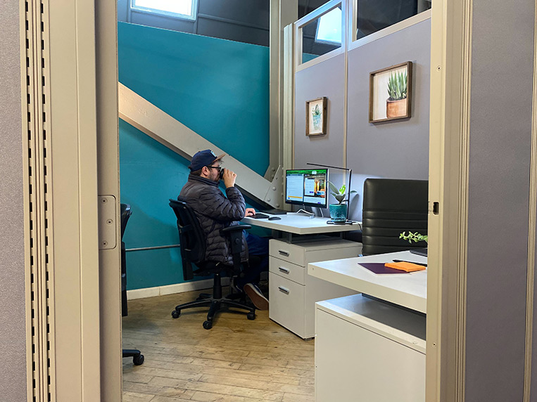 Man in small dedicated office at Cowork Connect drinking coffee