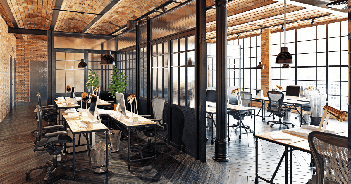 An office with large windows and multiple desks.