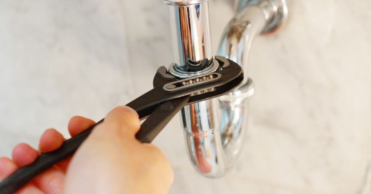 Fixing leaky plumbing under a sink by a plumber.