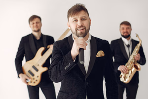 about-01 Vocalist and jazz band performing with guitars and saxophone in elegant black suits.