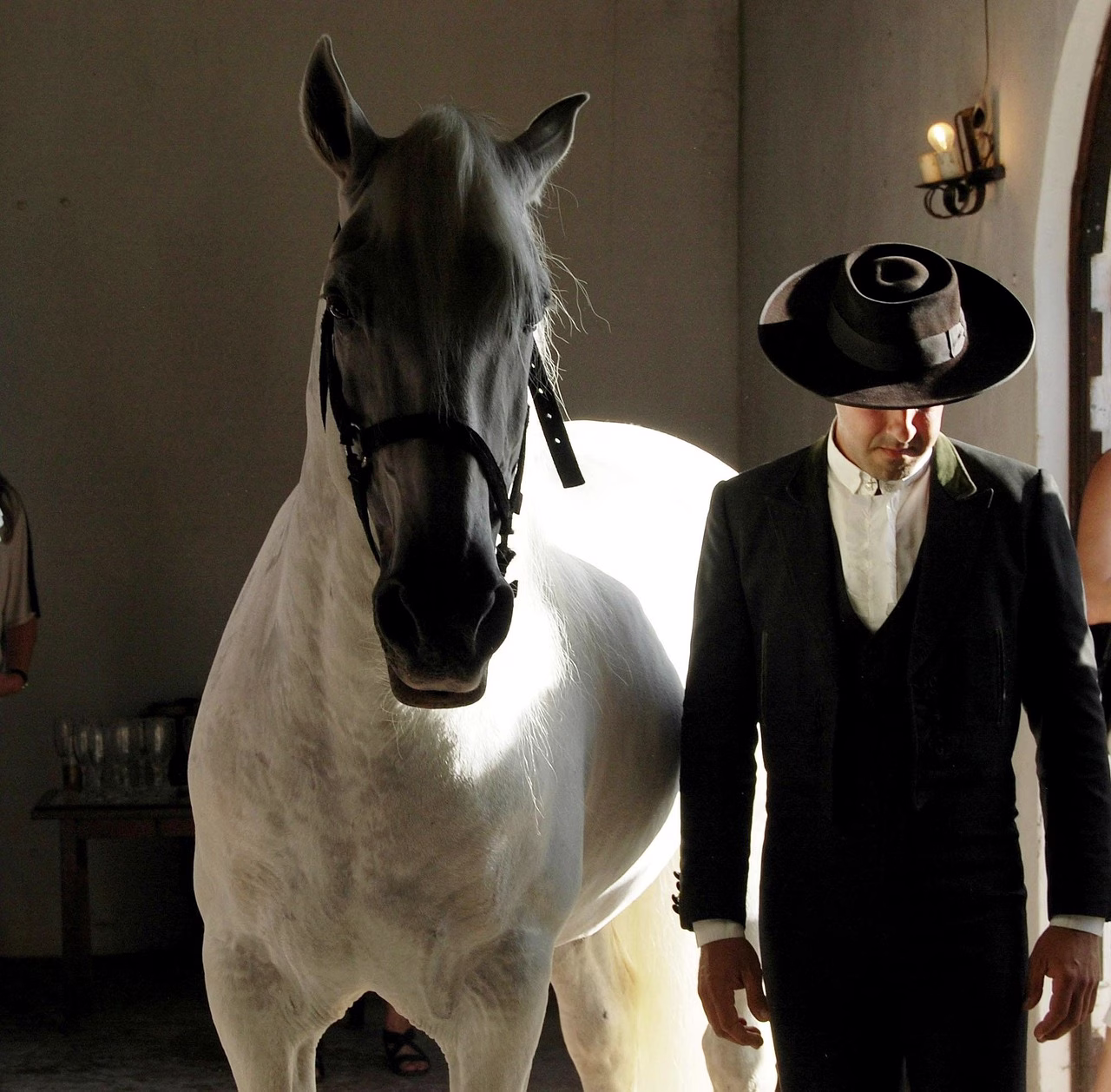A grey horse beside a man in a traditional Portuguese hat