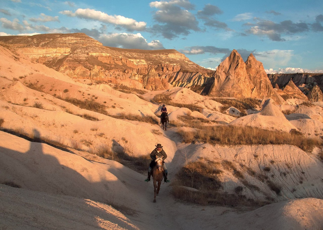 A rider on horseback in a Cappadocia valley at sunset