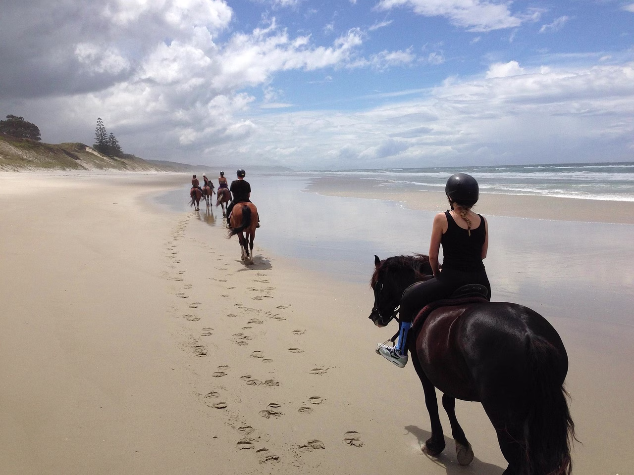 Riders on horseback on a long beach in New Zealand