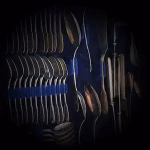 Une collection d'argenterie vintage est disposée en rangées sur un fond bleu foncé. L'ensemble se compose de fourchettes, cuillères et couteaux variés, soigneusement rangés dans des bandes protectrices.