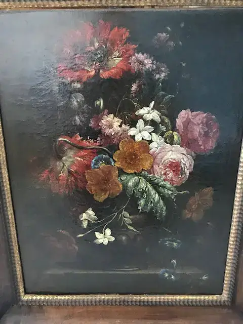 Un tableau encadré capture un bouquet luxuriant de fleurs rouges, roses et oranges sur un fond sombre, créant un affichage dramatique et vibrant qui invite à l'achat.