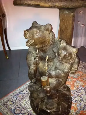 La charmante sculpture en bois représentant deux ours debout sur leurs pattes arrière, chacun tenant une canne de danse, ajoute une touche de gaieté à la pièce. J'achète cette charmante pièce, posée sur un tapis décoratif, avec en arrière-plan une table et une chaise en bois.
