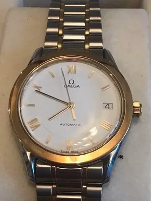 Cette montre-bracelet Omega en or et argent avec un bracelet en métal présente des chiffres romains, un affichage de la date à 3 heures et les mots « Omega » et « Automatic » élégamment inscrits. Sur fond beige, j'en suis conquis chaque fois que je l'achète à mon poignet.