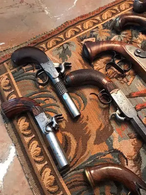 Une collection de pistolets à silex vintage ornés de gravures raffinées, idéale pour le collectionneur averti. Présentés sur un tapis aux motifs riches, ces pistolets sont dotés de poignées en bois sombre et de canons en métal aux motifs détaillés : l'essence même de « Ce que j'achète ».