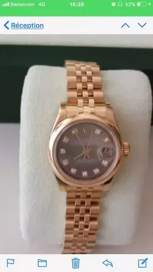 Une montre-bracelet en or avec une lunette et des index sertis de diamants sur un cadran noir. Elle est dotée d'un affichage de la date, élégamment serti sur un coussin blanc moelleux. C'est ce que j'achète pour allier luxe et sophistication.