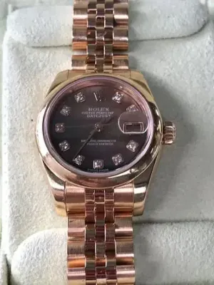 Présentée sur un coussin clair, cette montre Rolex en or avec cadran brun et index diamants respire le luxe et l'élégance. Son bracelet à maillons et son guichet de date rehaussent son charme. Acquérez ce chef-d'œuvre pour sublimer instantanément votre style.