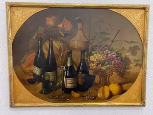 Une nature morte représente des bouteilles de vin, des verres, une carafe et un assortiment de produits, dont des fruits variés comme des oranges et des raisins, ainsi qu'une composition florale dans un vase décoratif. La composition repose sur une surface texturée avec un fond aux tons chauds et terreux.