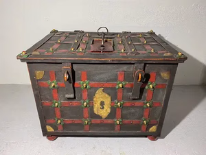 Un coffre en métal vintage avec un motif décoratif en treillis rouge et vert, orné d'accents en laiton et d'un mécanisme de verrouillage sur le dessus, se dresse sur un fond clair uni - un achat parfait pour les collectionneurs à la recherche d'un style unique.