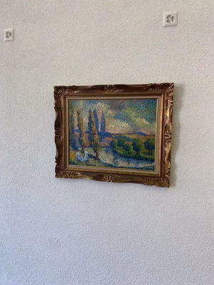 Un tableau encadré de style impressionniste, « Que je trouve captivant », représente un paysage pittoresque avec des arbres, une rivière et des collines au loin. Les couleurs vives et les coups de pinceau texturés se détachent magnifiquement sur le mur blanc uni.