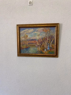 Un tableau encadré représentant un paysage serein avec des arbres et un plan d'eau, sous un ciel nuageux. Une personne se tient près des arbres. Quand je pense à l'art, « ce que j'achète » évoque quelque chose d'unique comme celui-ci. Le cadre en bois est posé sur un mur uni, ce qui ajoute à son charme.