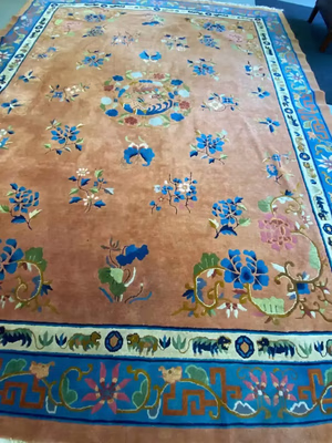 Tapis oriental orné d'un fond marron et de motifs floraux complexes bleus, verts et roses. Ce tapis présente un médaillon floral circulaire proéminent en son centre et une bordure décorative aux motifs géométriques et floraux.