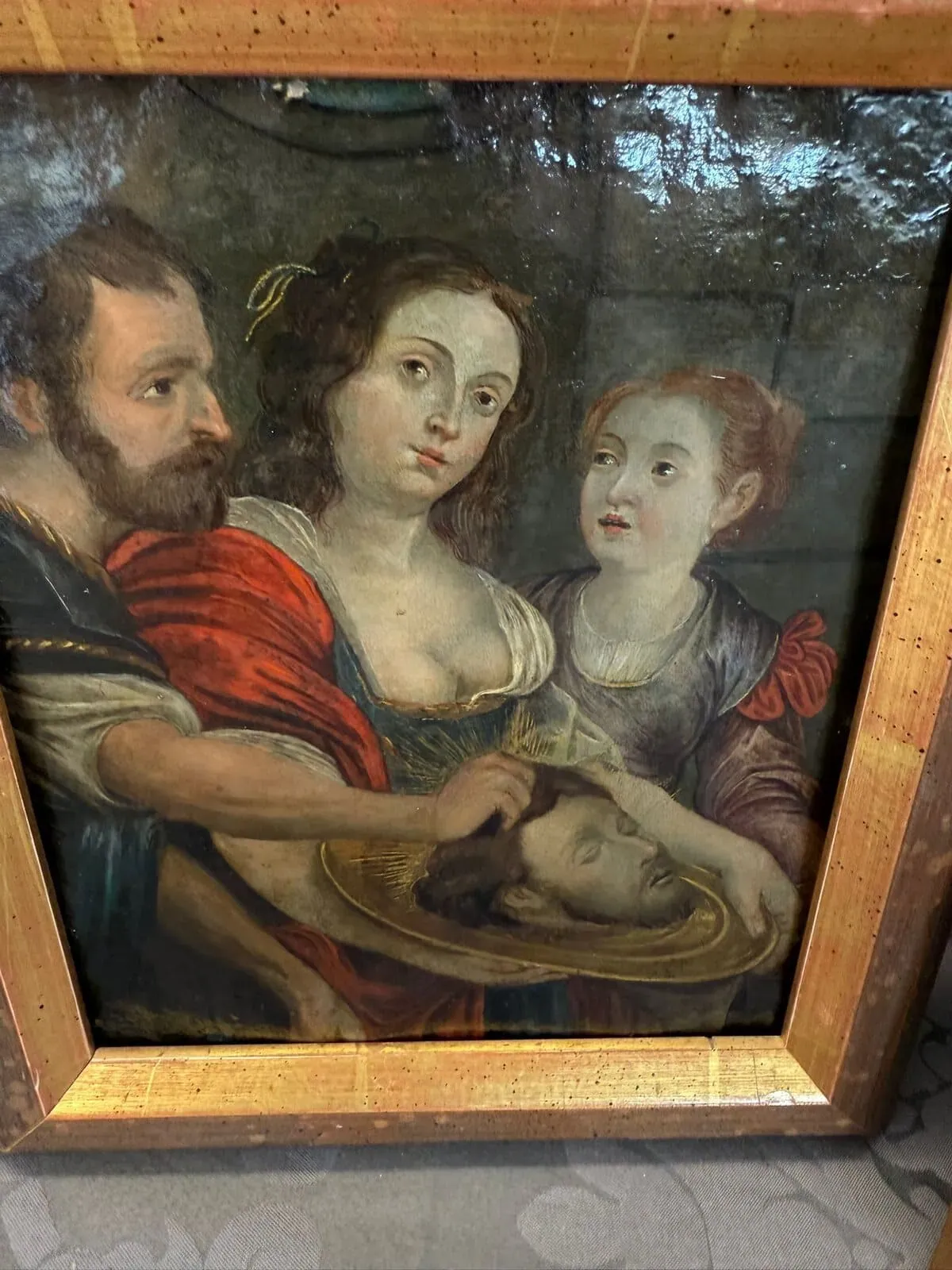 Un tableau encadré représente un homme barbu, une femme tenant un plateau en or avec la tête coupée d'un homme et une jeune fille à côté d'eux, tous vêtus de vêtements historiques, sur fond de Soleure.