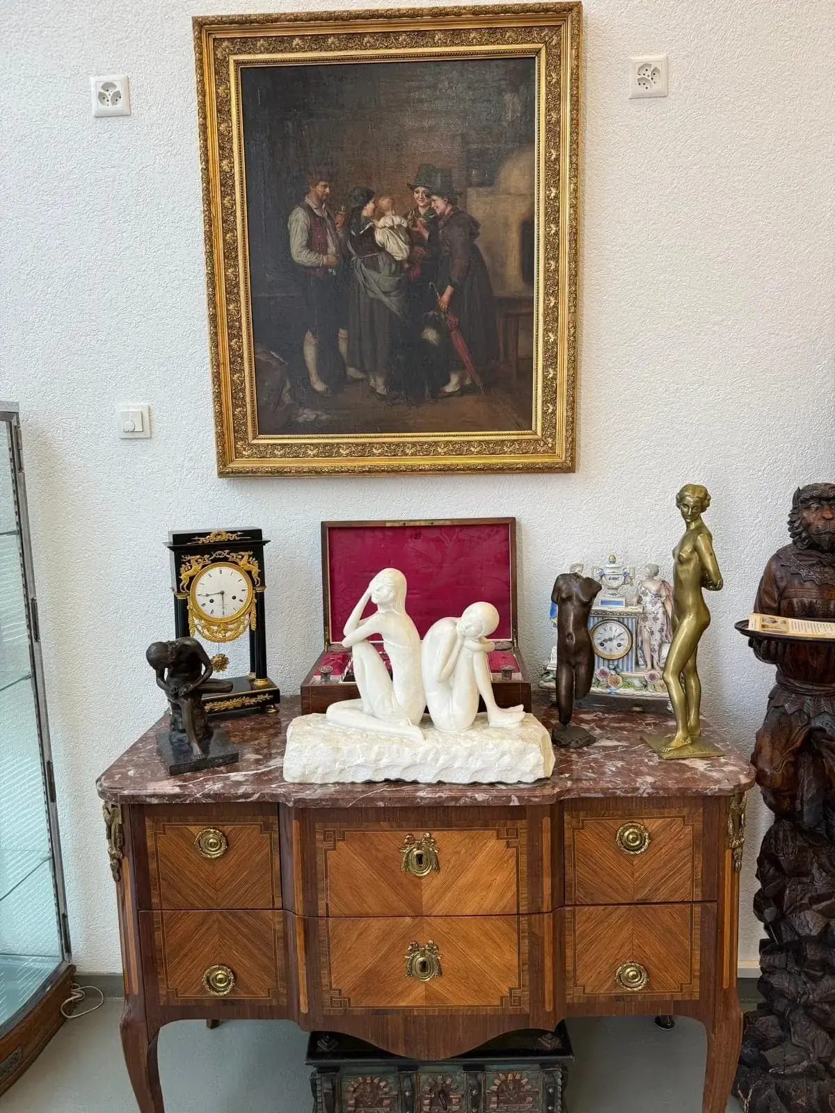 Tableaux et sculptures sur une commode ornée.
