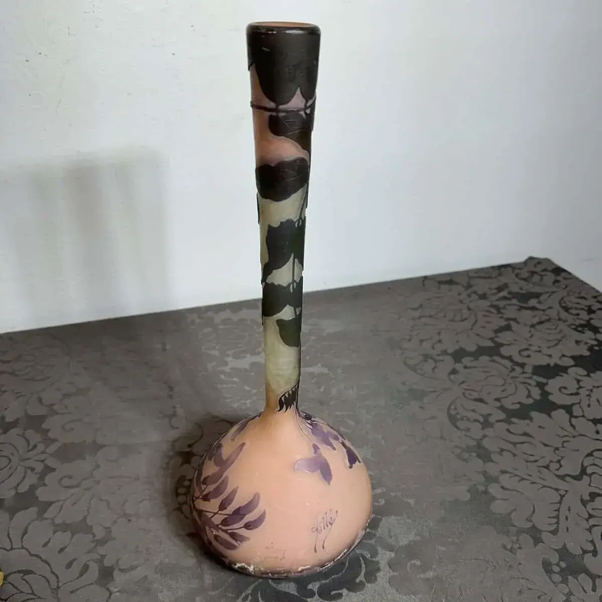 Vase étroit avec motifs floraux sur table grise.