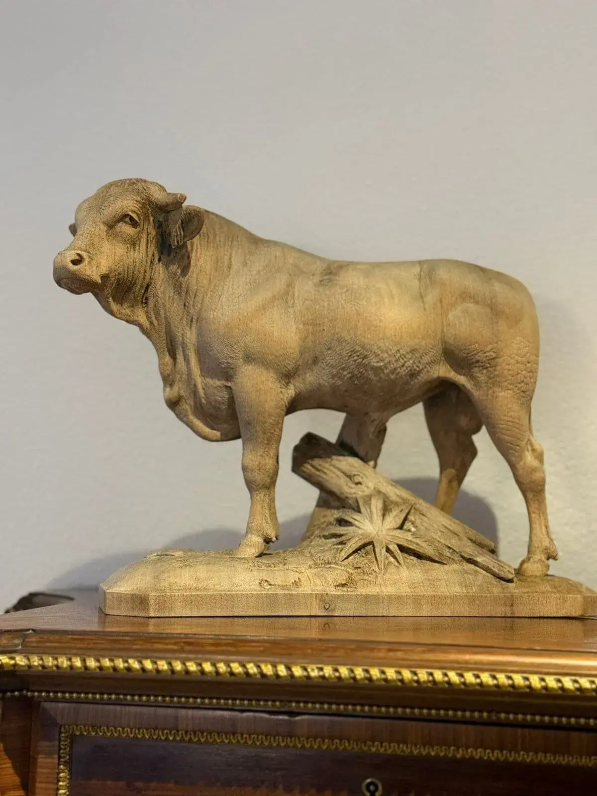 Statue en bois d'un taureau sur meuble.