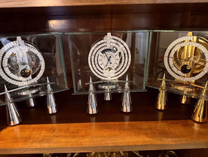 Trois horloges mécaniques transparentes sur étagère en bois