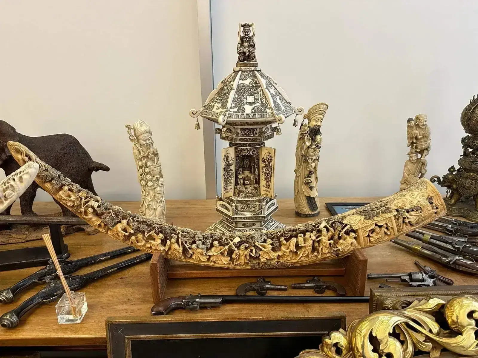 Objets anciens asiatiques sculptés exposés sur une table.