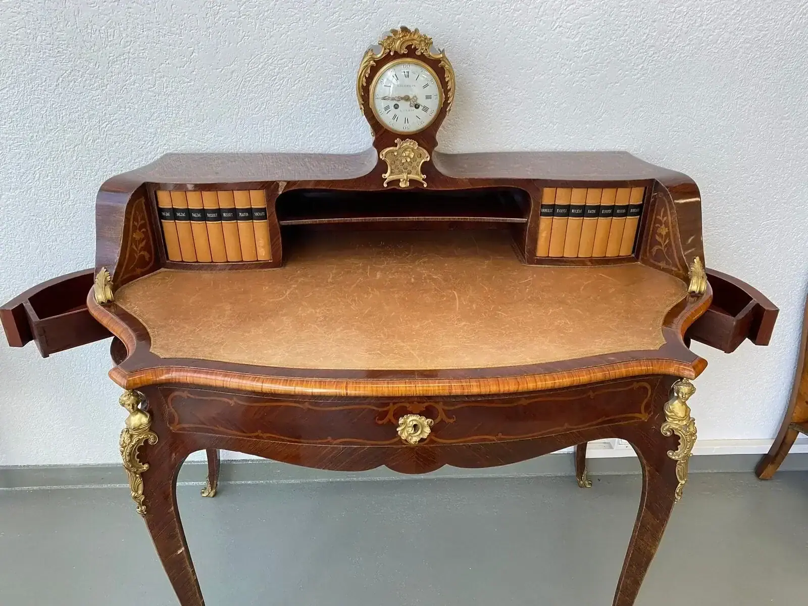 Bureau ancien en bois avec horloge et livres.