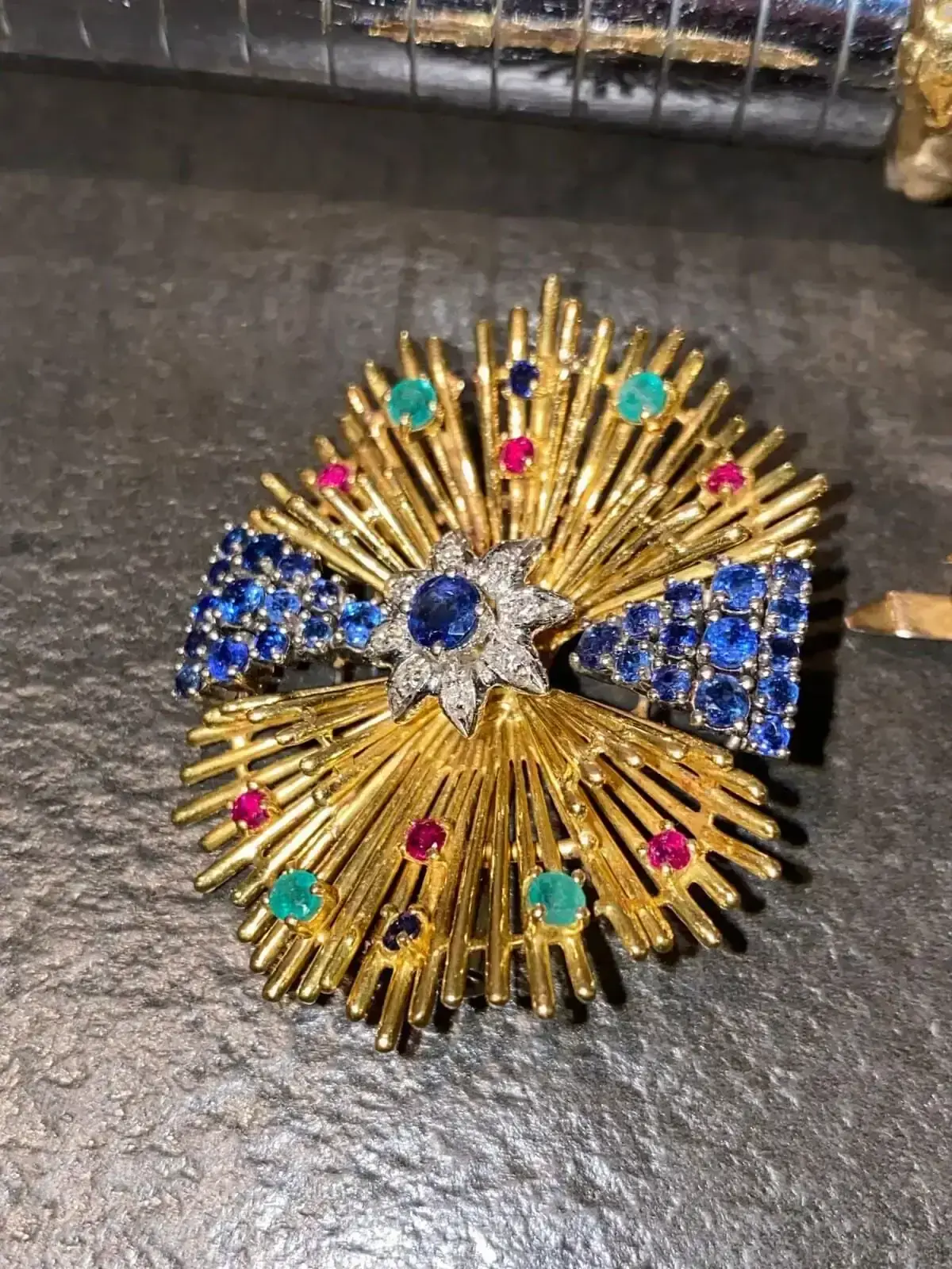 Broche dorée ornée de pierres colorées.