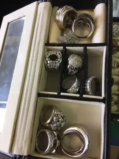 Boîte à bijoux avec plusieurs bagues argentées ornées.