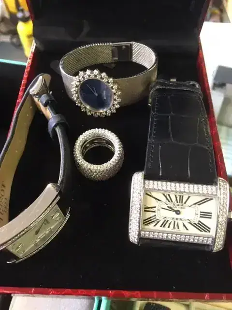 Boîte avec montres de luxe et bague argentée.