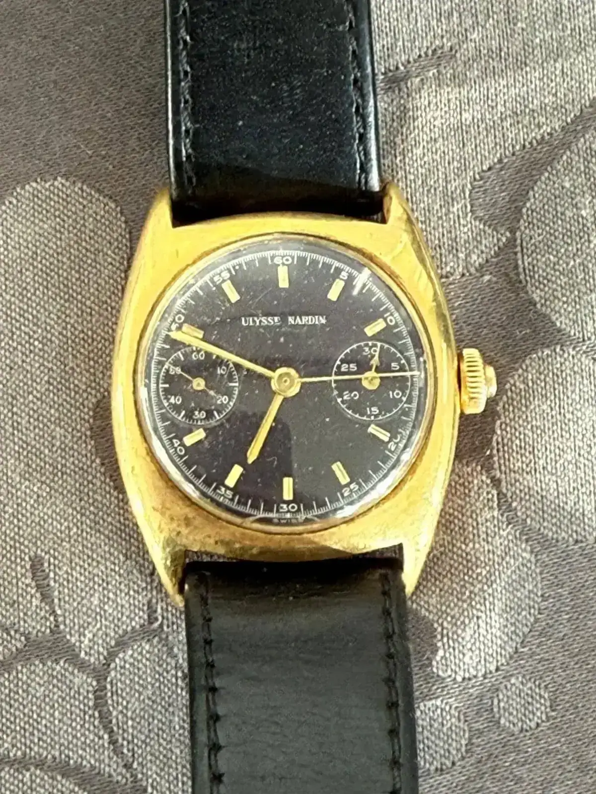 Montre dorée vintage avec bracelet noir.