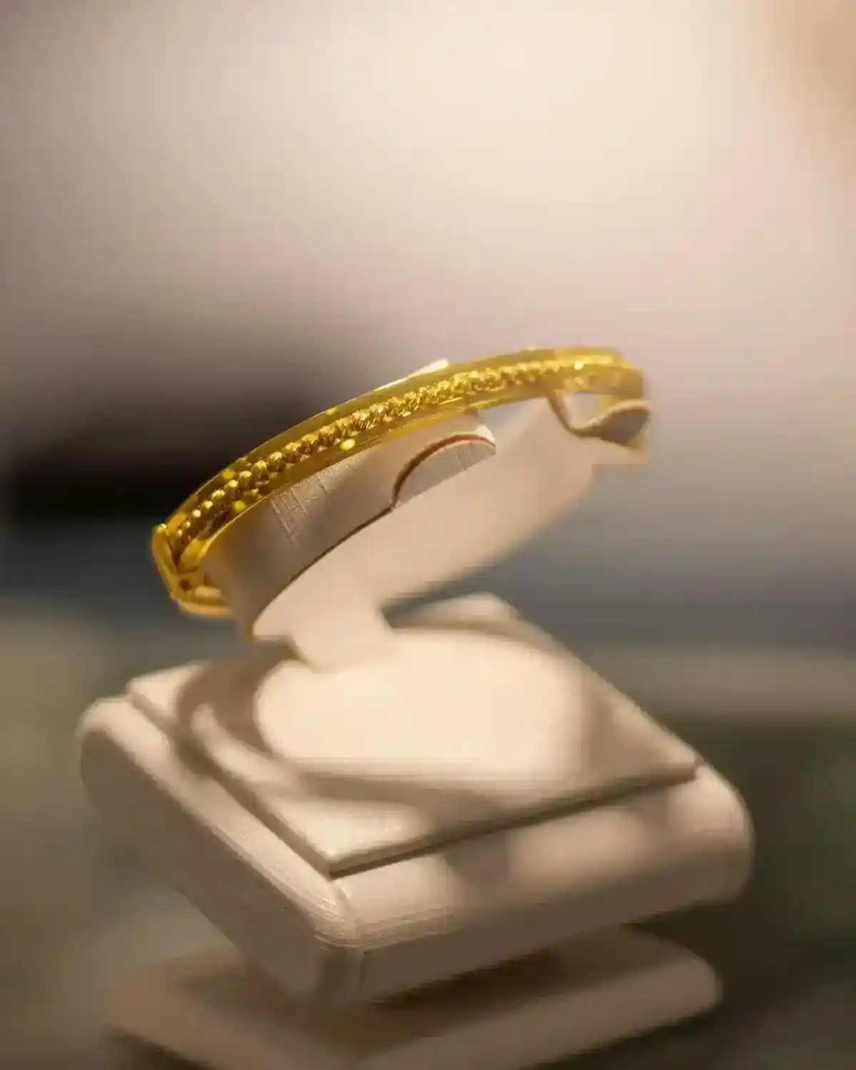 Close-up of a luxurious gold bracelet elegantly displayed on a stand.