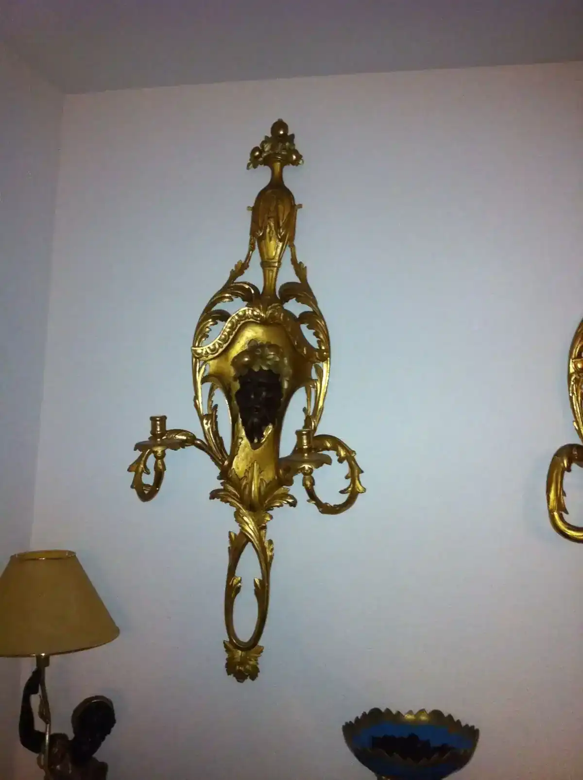 Applique murale dorée décorative avec deux bras.