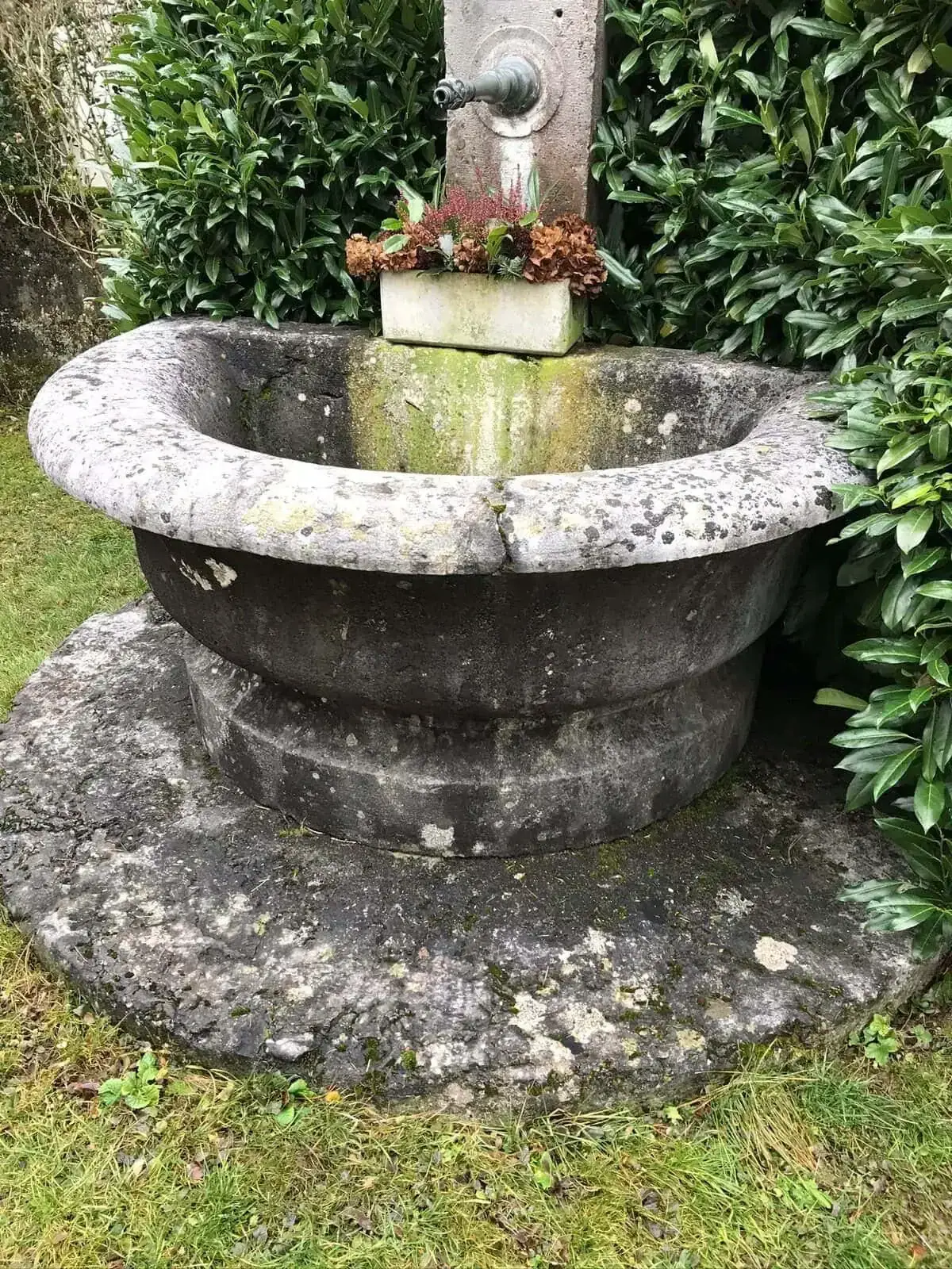 Ancienne fontaine en pierre dans un jardin verdoyant