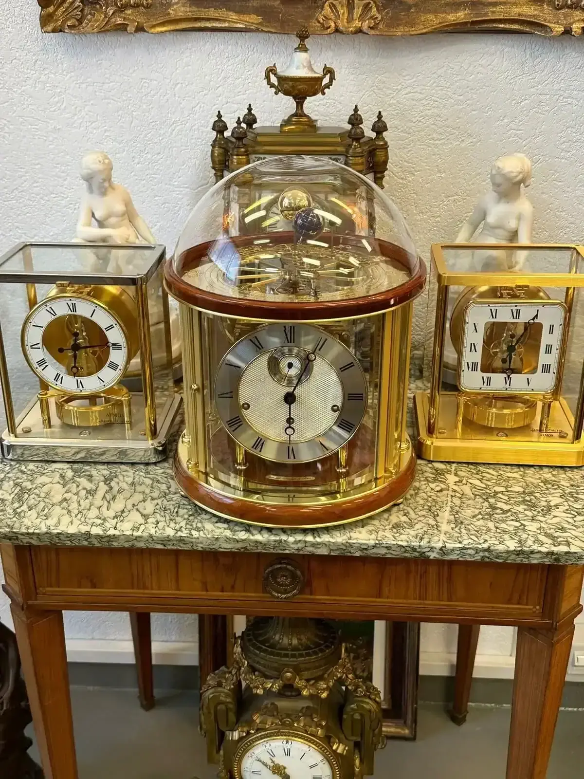 Trois horloges anciennes dorées sur table en marbre.