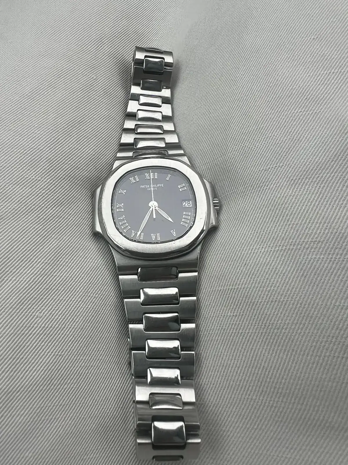 Montre en acier avec cadran gris foncé.